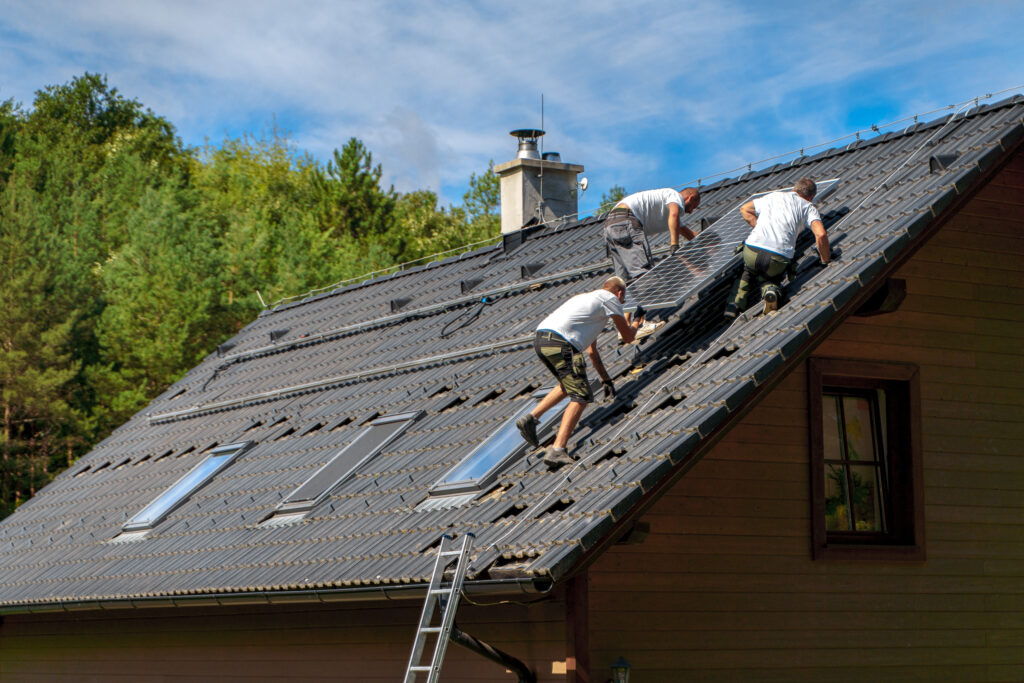 Professional roofing team installing solar panels and roofing components on a residential home with skylights.