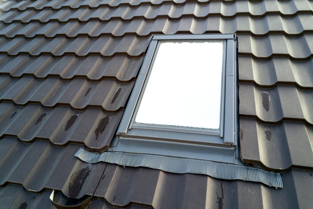 close up of new attic plastic window installed in shingled house roof. professionally done building and construction work, roofing and installation concept.