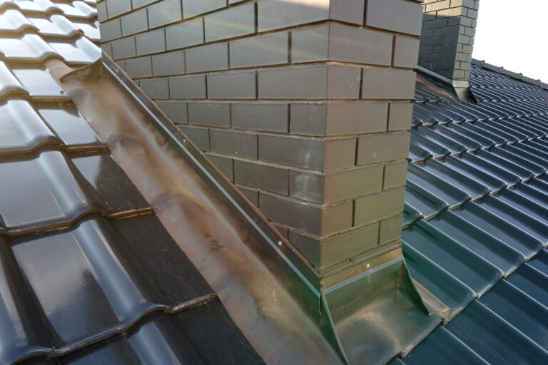 closeup of brick chimney on house roof top covered with ceramic shingles. tiled covering of building
